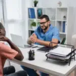 due persone alla scrivania di un ufficio uno di fronte all'altro uno