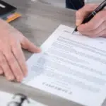 immagine di un documento su una scrivania con mani che firmano