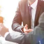 primo piano del busto di due persone in giacca e cravatta che gesticolano tra di loro